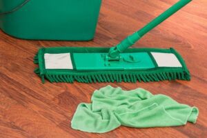 Green colour mop with green colour cloth on a wooden floor